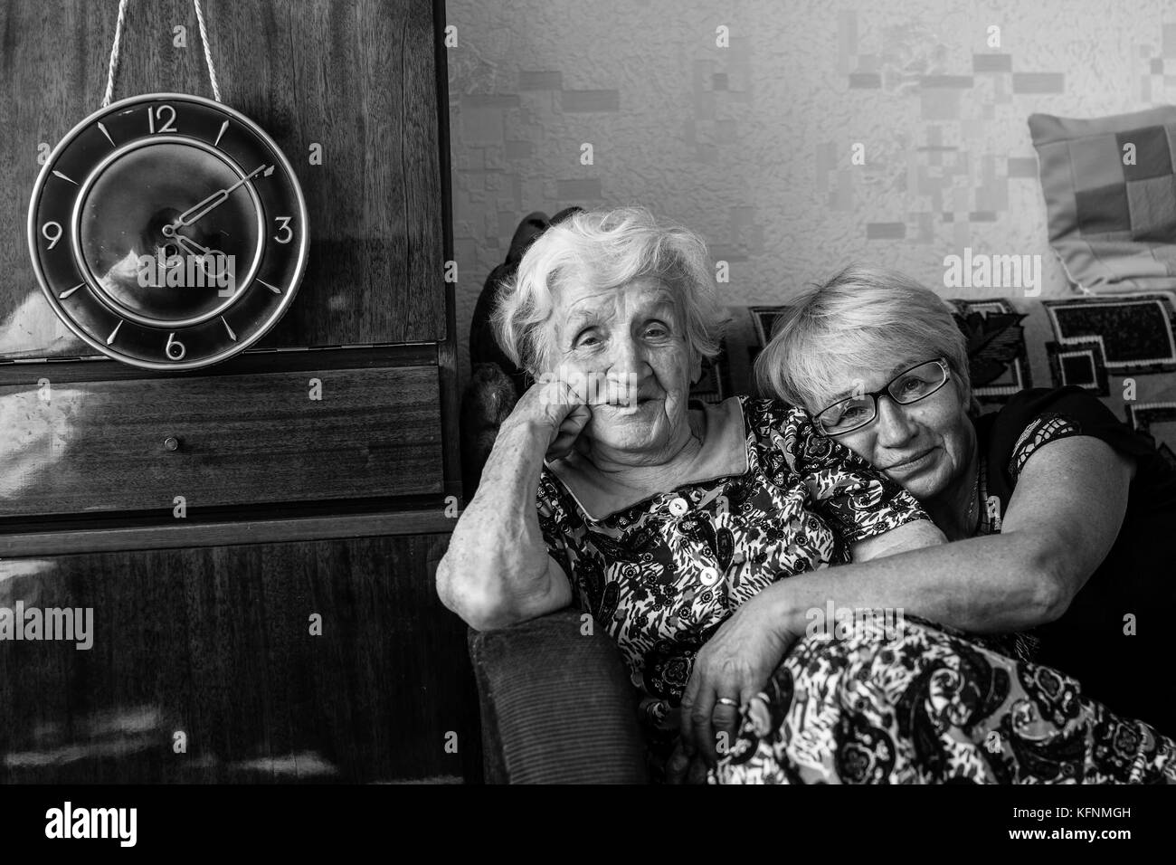 Elderly woman sitting on the couch with his adult daughter. Stock Photo