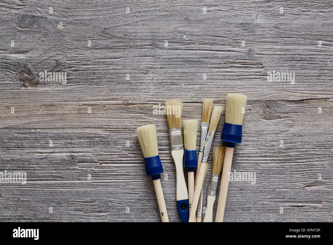 three paintbrushes unorganised on raw wooden table Stock Photo