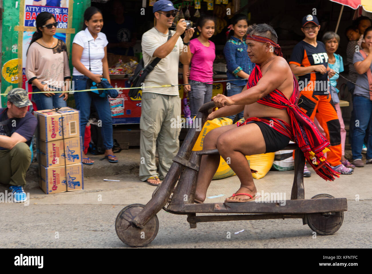 Ifugao men taking part in a wooden scooter race as part of the annual