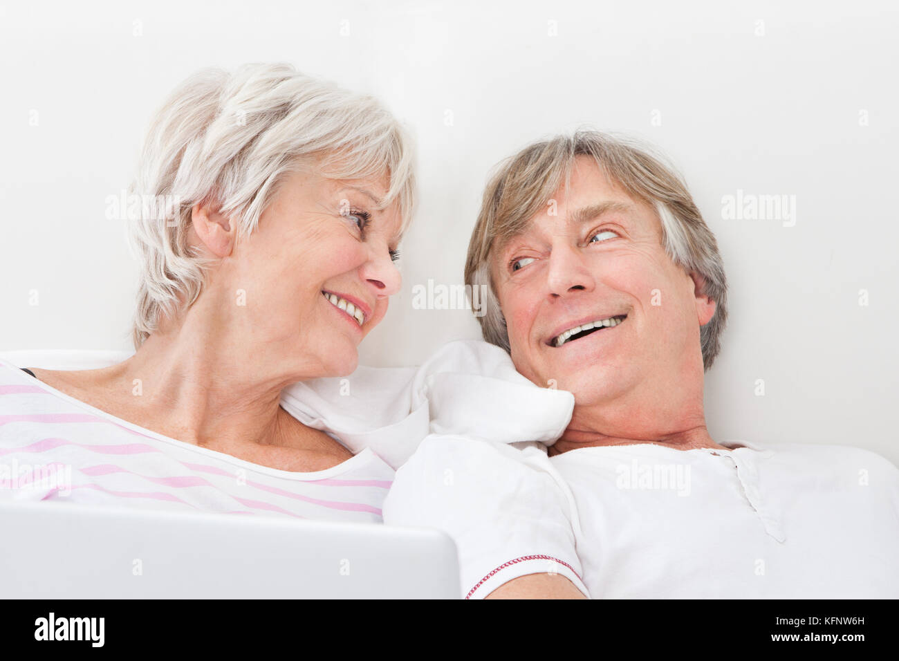 Portrait Of Loving Senior Couple Lying On Bed Stock Photo - Alamy