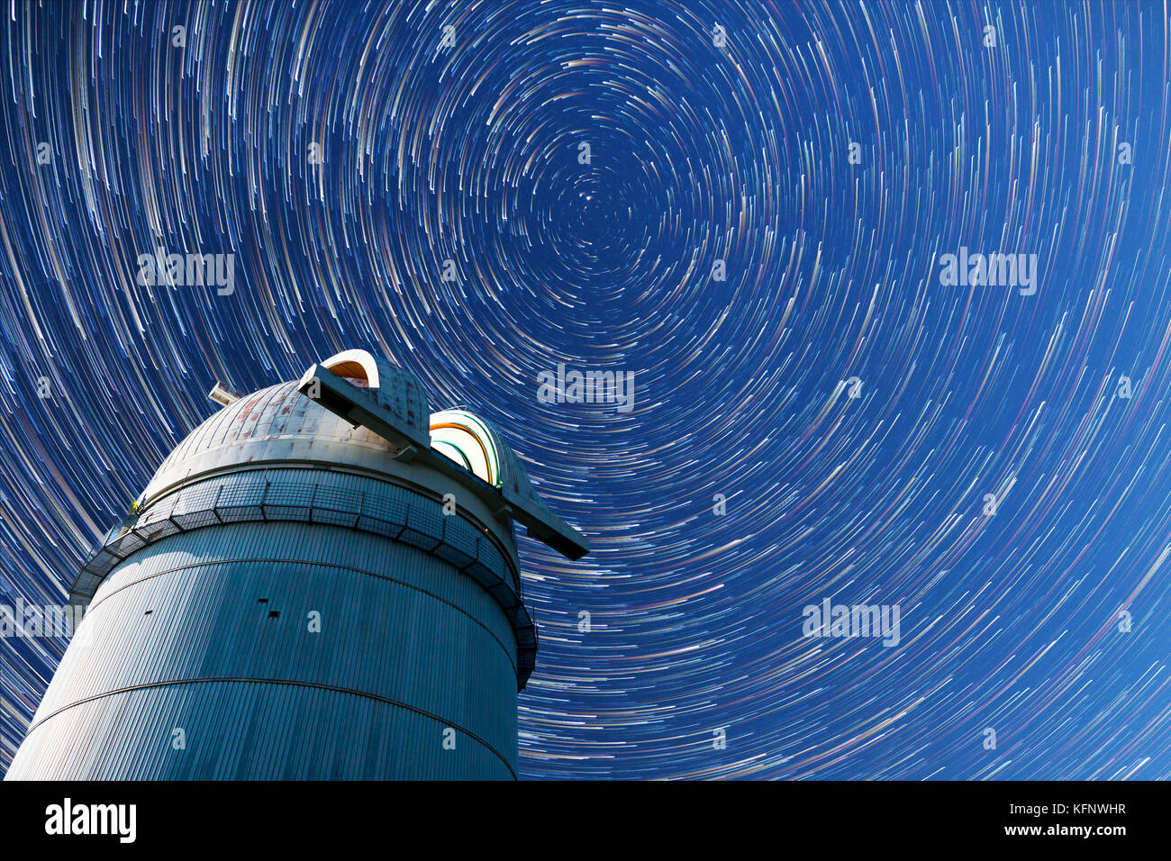 Astronomical observatory under the night sky stars. Blue sky with hundreds of stars of the Milky way. Timelapse in comet mode. Stock Photo
