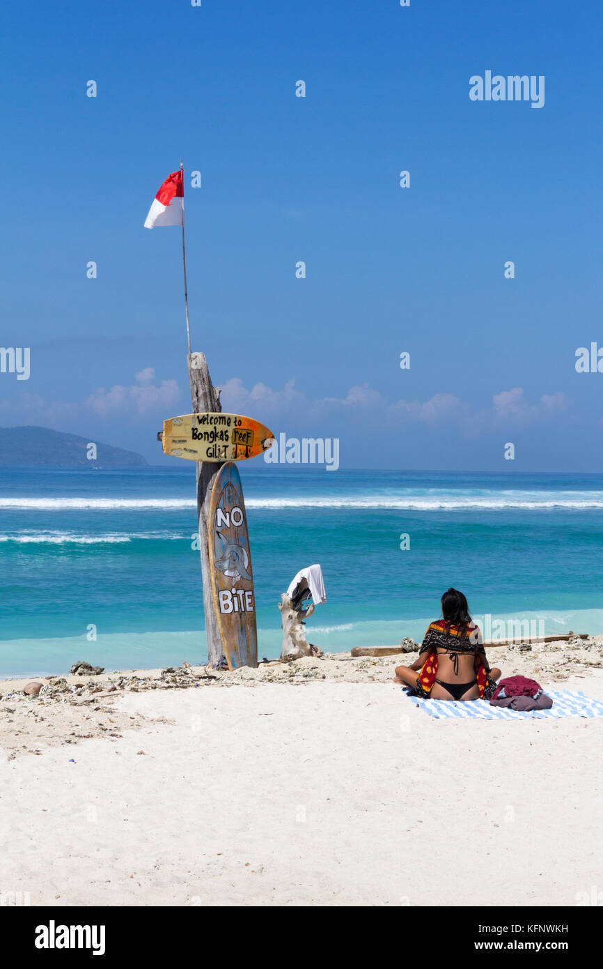 Girl sits on the beach looking out to sea, Bonkas reef, Gili Trawangan, Indonesia Stock Photo
