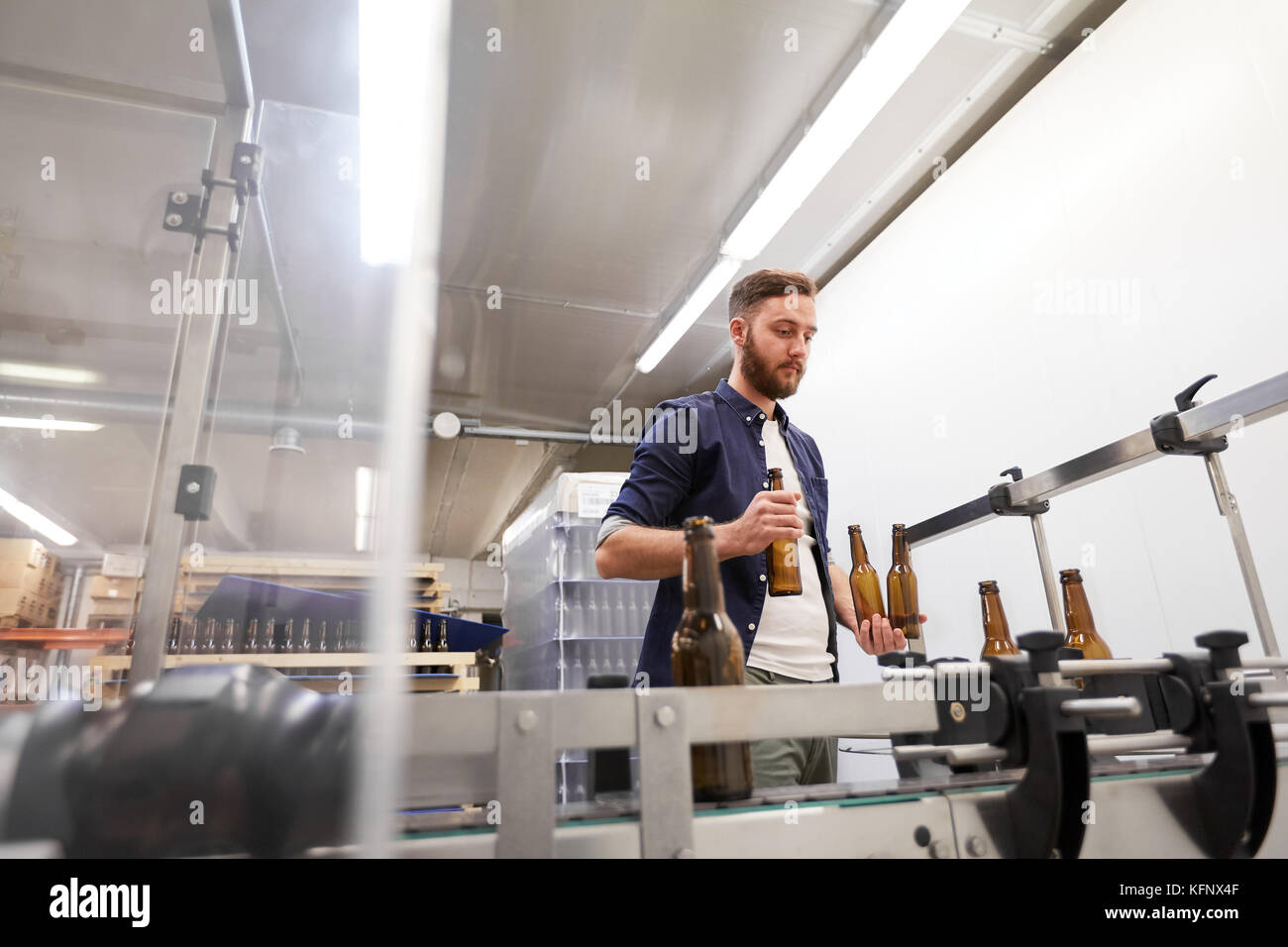 men with bottles on conveyor at craft beer brewery Stock Photo