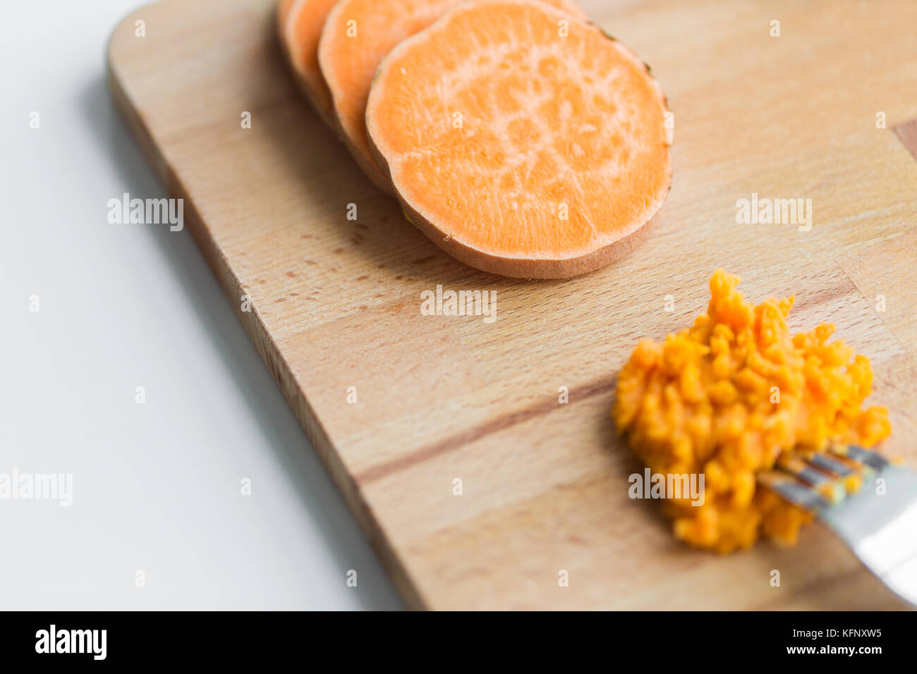 hand with fork making mashed batata on board Stock Photo
