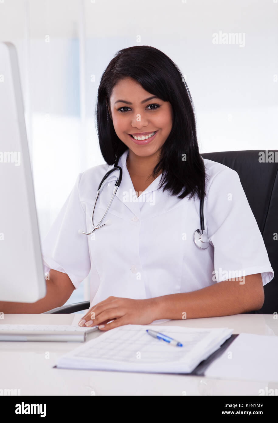 Pretty Young Confident Doctor Using Computer In Clinic Stock Photo