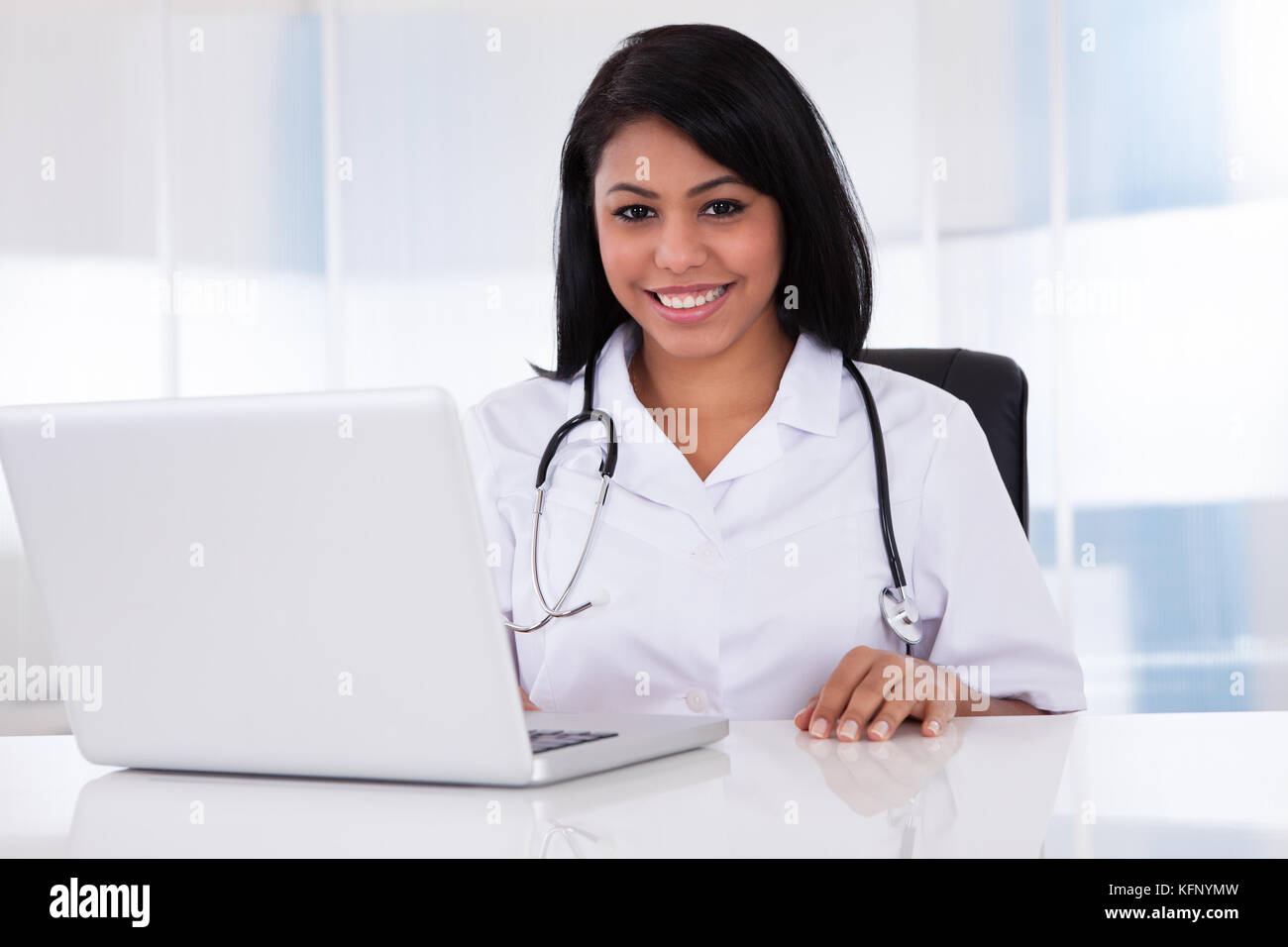 Pretty Young Confident Doctor Using Laptop In Clinic Stock Photo