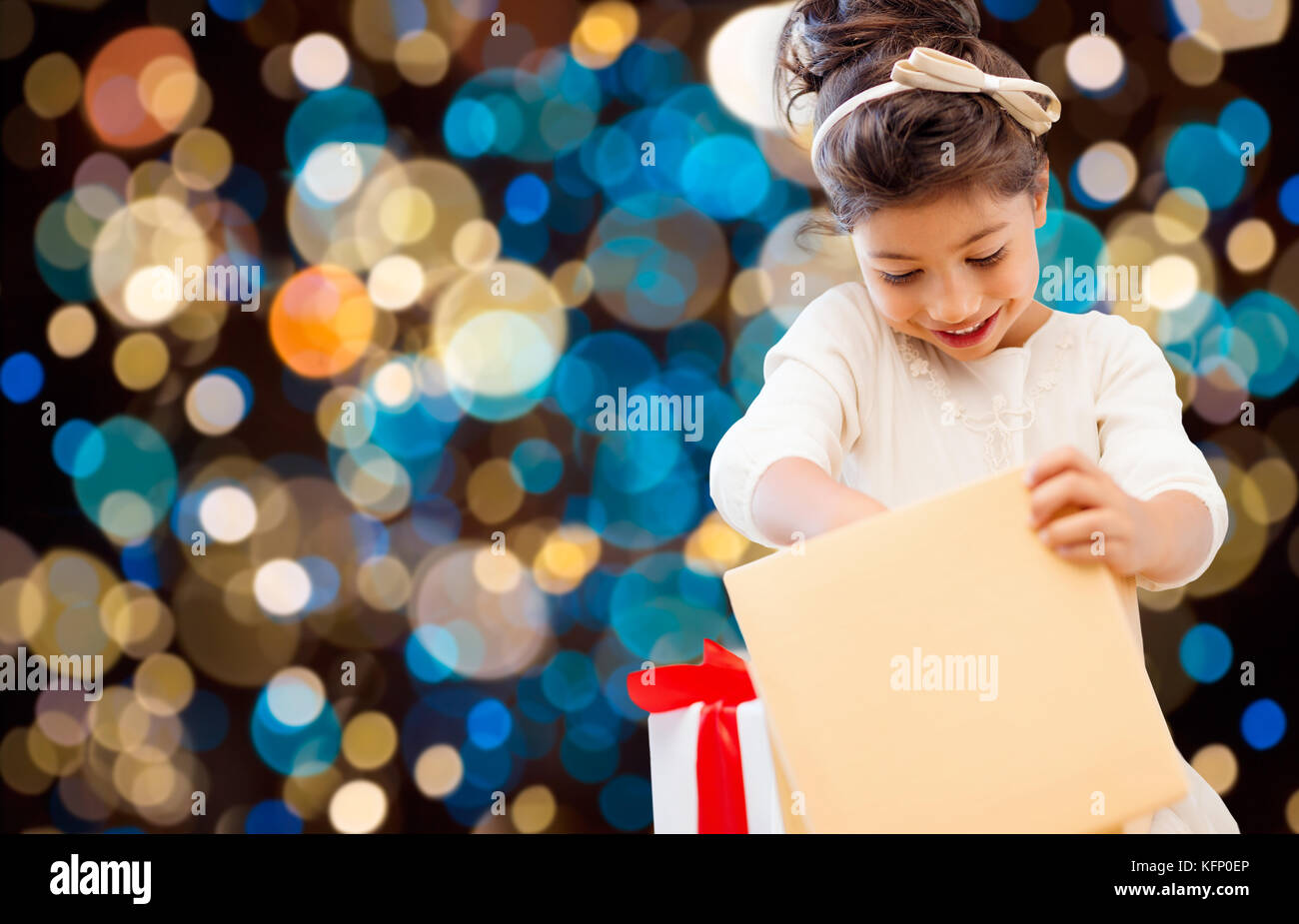 smiling little girl with gift box over lights Stock Photo - Alamy