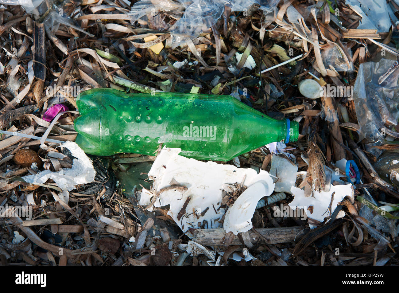 A discarded green plastic fizzy drink bottle amongst multiple bits of plastic washed onto the beach on the Balearic island of Menorca Stock Photo