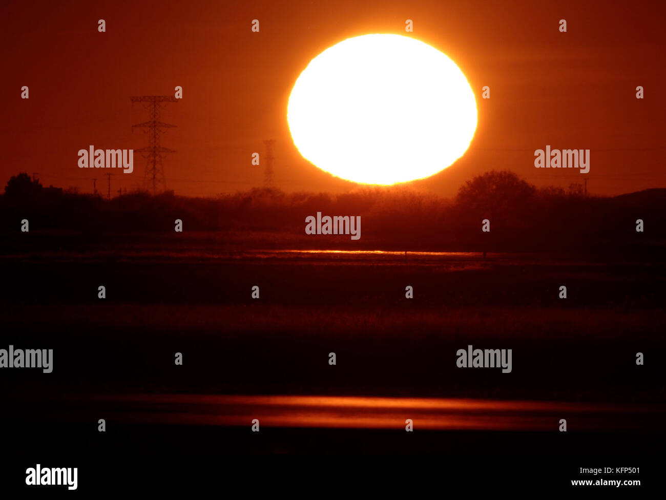 Sun seen at sunset on the horizon to the west of the capital of Sonora, located in the desert northwest of Mexico.    The Sun is a star of spectral type G2 which lies in the center of the solar system and is the largest source of electromagnetic radiation of this planetary system. Earth and other bodies orbit around the sun.    Distance to Earth: 149,600,000 km  Radio: 696,000 km  Surface temperature: 5,778 K  Mass: kg 1,989E30  Absolute size: 4.83  Magnitude: -26.74 Stock Photo