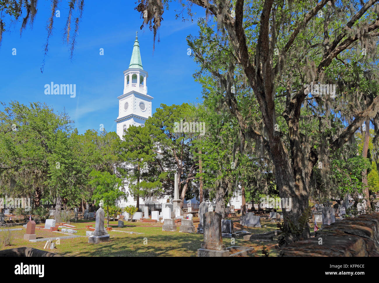 Spire main building and graveyard framed by Spanish moss-covered trees at the parish church of St. Helena in the historic district of downtown Beaufor Stock Photo