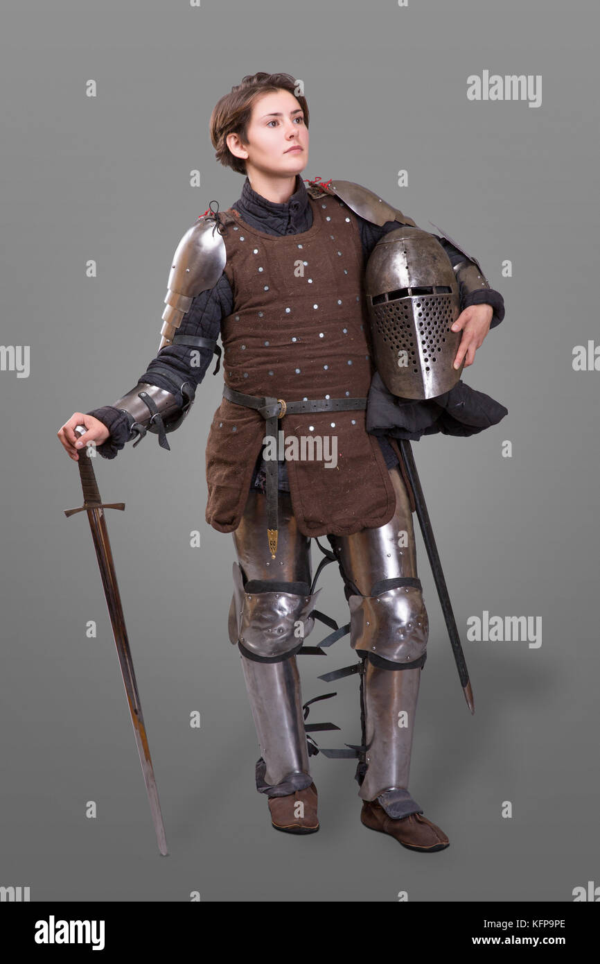 young woman in Knight Armour holding helmet in one hand and sword on