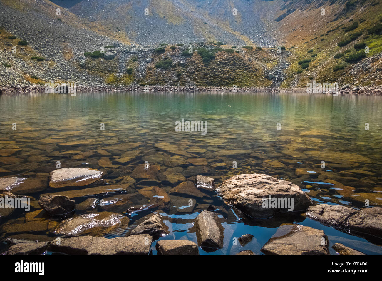 Rocks at the shore of a glacial lake high in the Mountains. Stock Photo