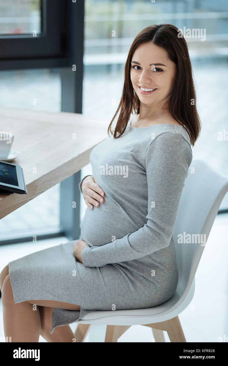 Amused pregnant woman sitting on the chair Stock Photo