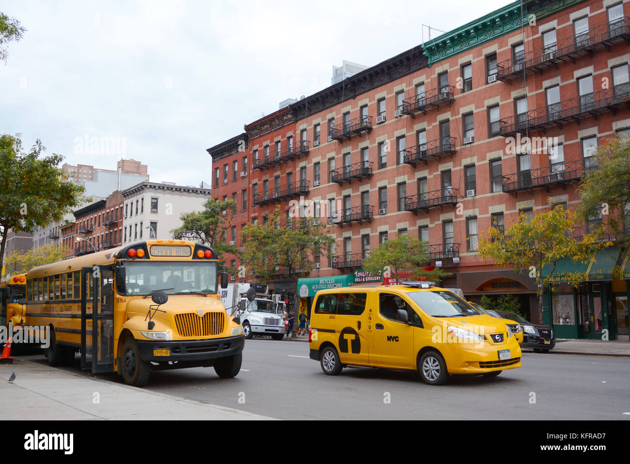 NEW YORK - OCTOBER 23, 2017: Yellow school bus and NYC taxi cab on 10th Avenue in Manhattan. Both are iconic American vehicles seen on the city street Stock Photo