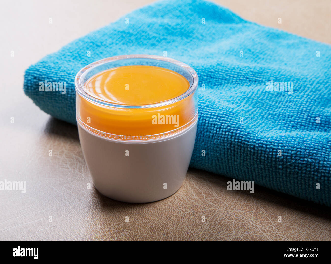 jar with cosmetic cream and a blue towel on the table Stock Photo