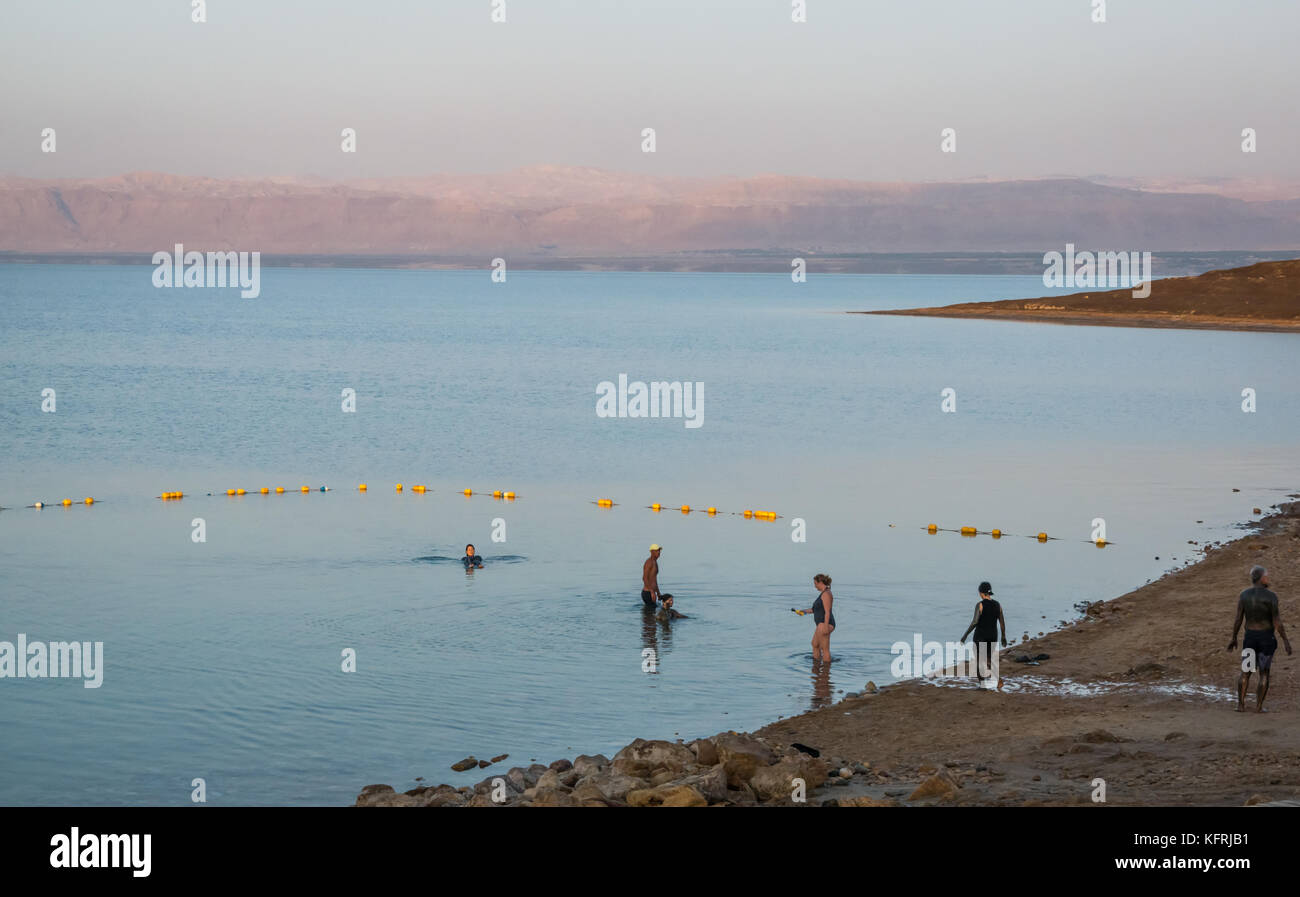 Early morning, Holiday Inn Dead Sea beach resort, with people covered in mud and floating in salty water, and view to West Bank, Jordan, Middle East Stock Photo