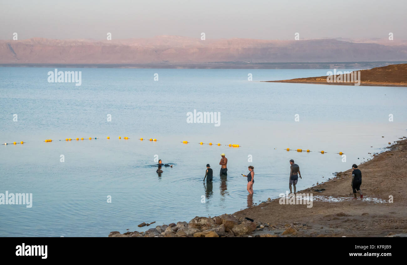 Early morning, Holiday Inn Dead Sea beach resort, with people covered in mud and floating in salty water, and view to West Bank, Jordan, Middle East Stock Photo