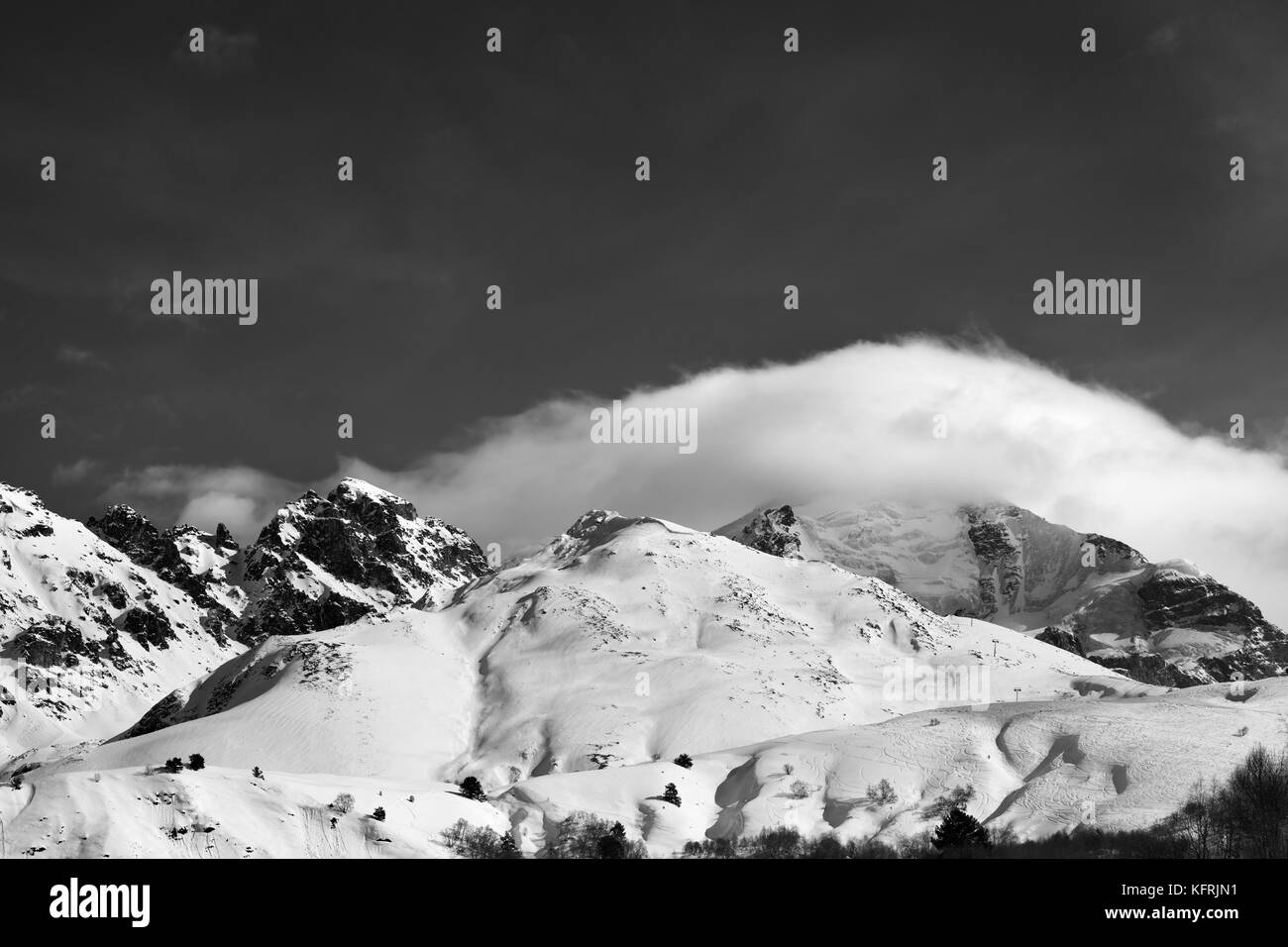 Black and white mountains in clouds and off-piste slope in winter ...