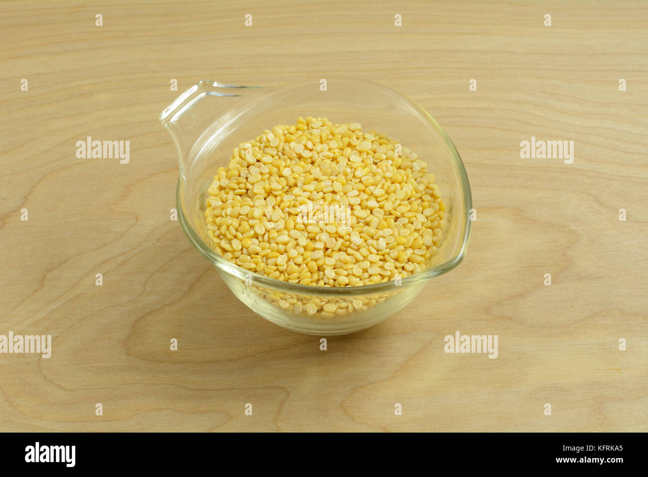 Glass measuring cup full of moong dal or yellow split mung beans Stock Photo