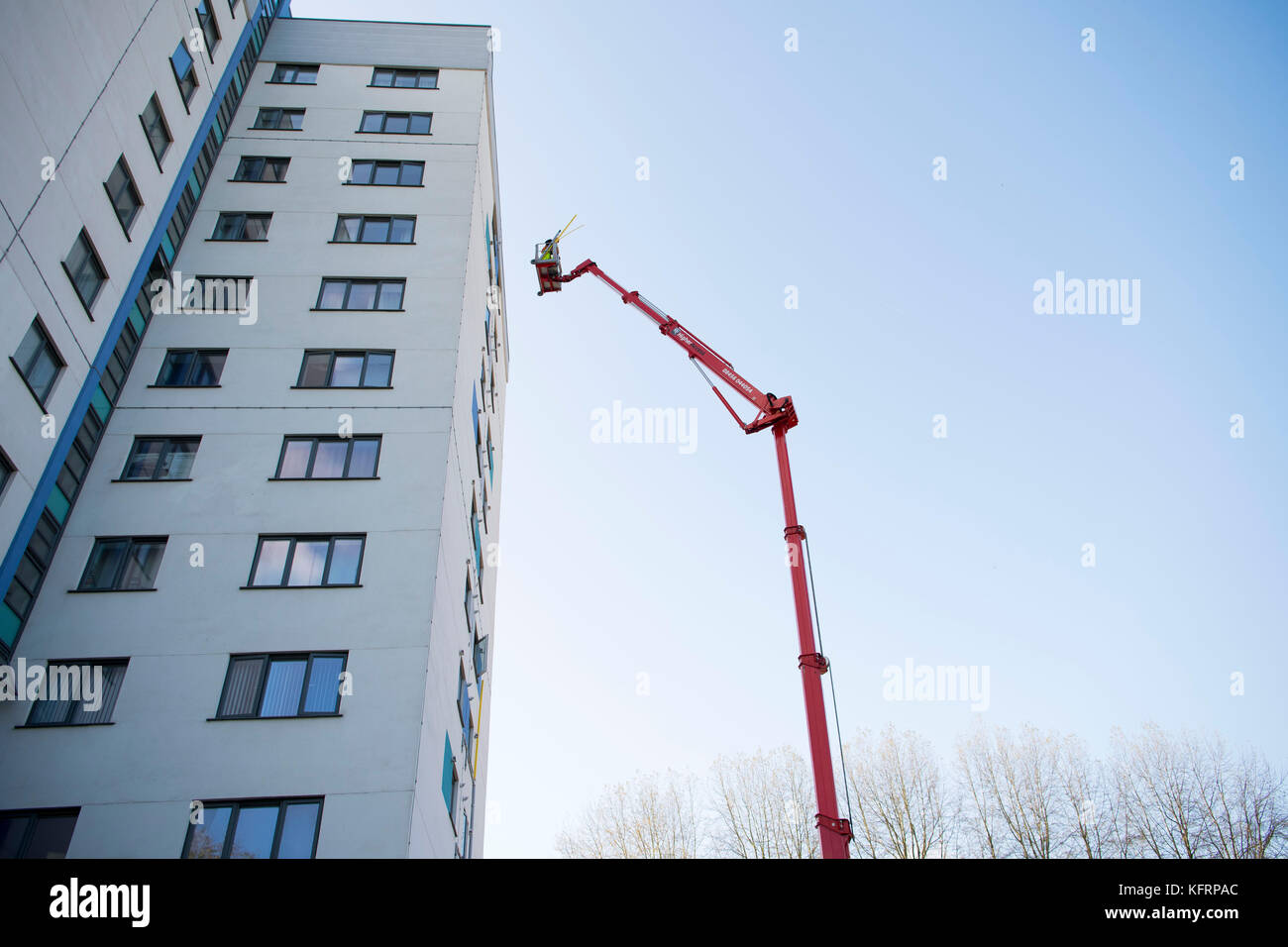 Cherry picker elevated lift alongside a tower block of council flats for maintenance in Wales, UK. Stock Photo