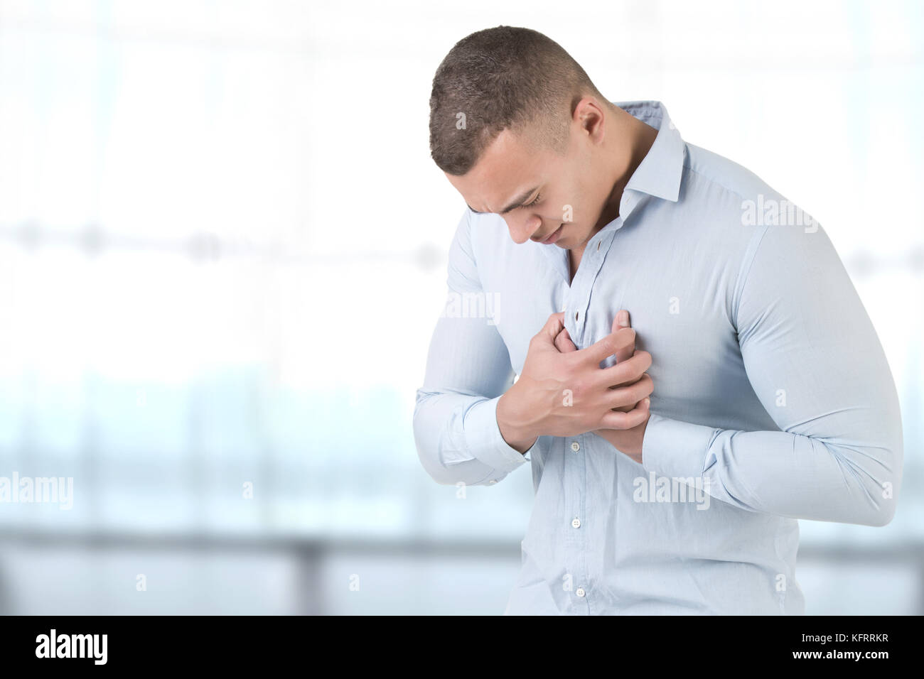 Man having a pain in the heart area, in a blue bacckground Stock Photo
