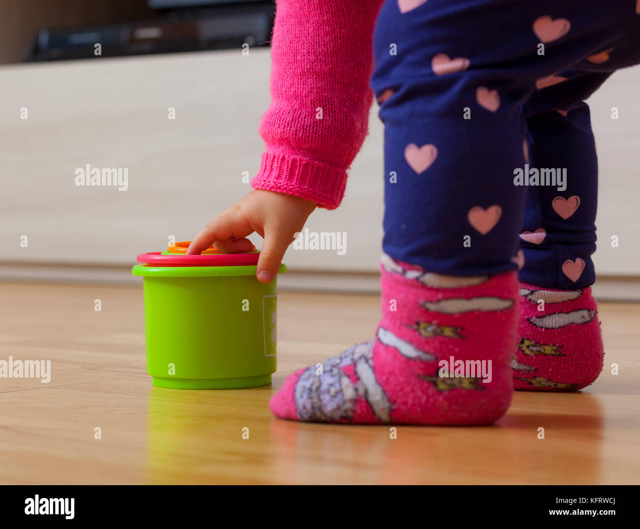Toddler baby girl plays with colored cups, toy for cognitive development. Stock Photo