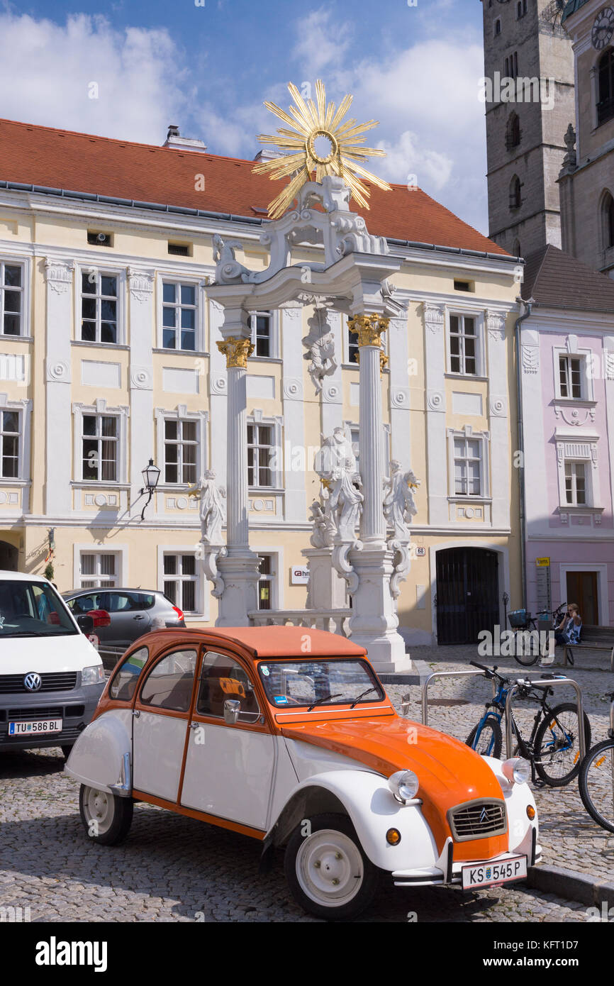 A classic Citroën 2CV car in front of the Dreifaltigkeitssäule (holy trinity column) in Stein an der Donau, UNESCO World Heritage Site, Lower Austria Stock Photo