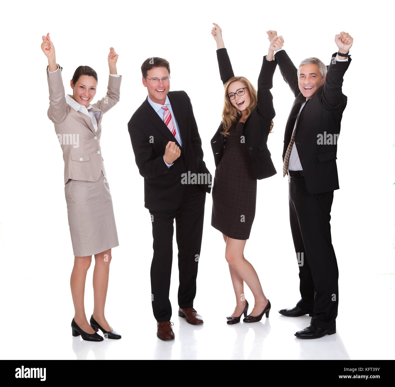 Four excited diverse professional businesspeople celebrating a success laughing and raising their arms in the air isolated on white Stock Photo