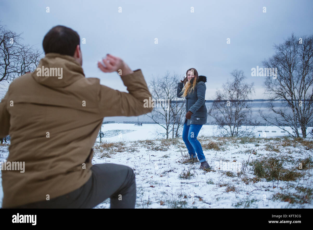 Happy young couple in winter clothes playing snowballs outdoors Stock ...