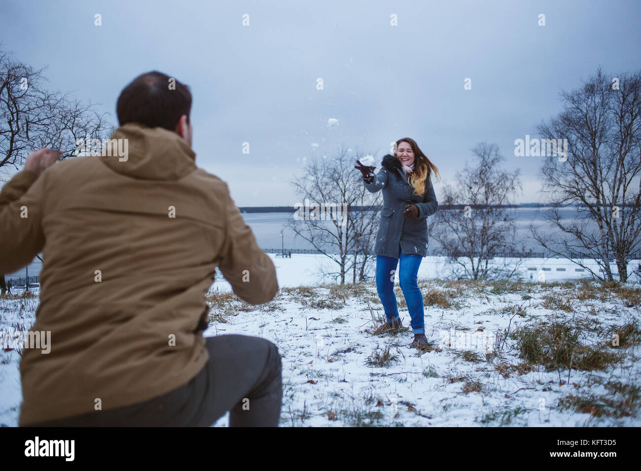 Happy young couple in winter clothes playing snowballs outdoors Stock ...