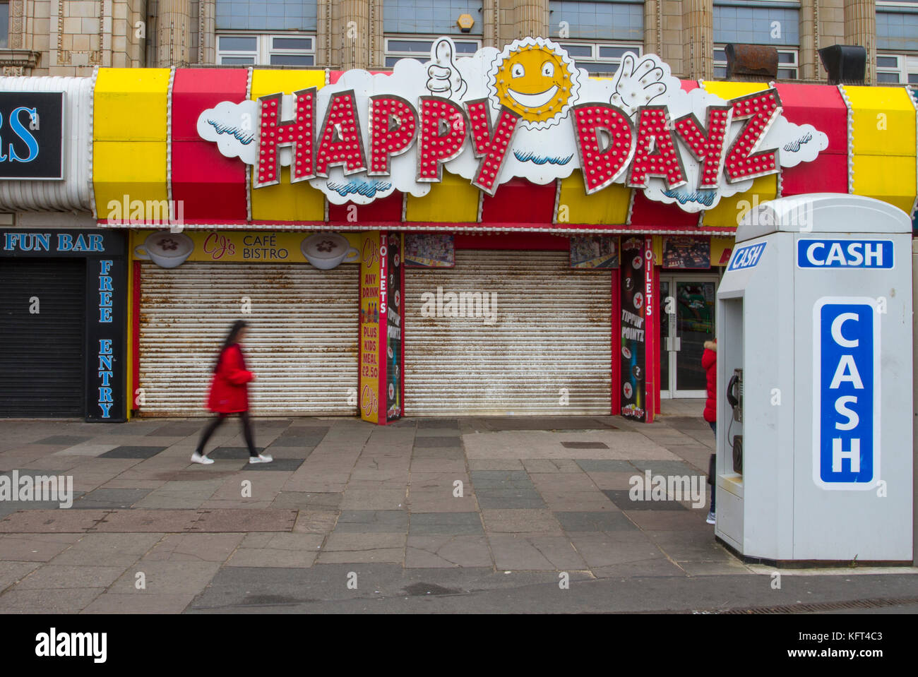 'Happy Days' sign; Out of focus figures passing Golden Mile Retail units To Let, Closed, Closing down, Shuttered shops, businesses in decline, with poor retail sales.   The Malaise affecting British Seaside resorts. Blackpool, Lancashire, UK Stock Photo
