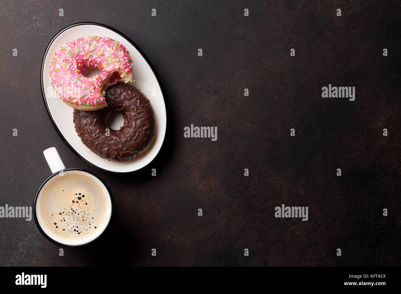 Coffee cup and colorful donuts on stone table. Top view with copy space ...