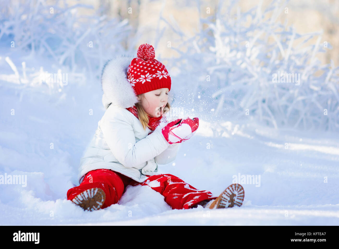 Child playing with snow in winter. Little girl in colorful jacket and ...