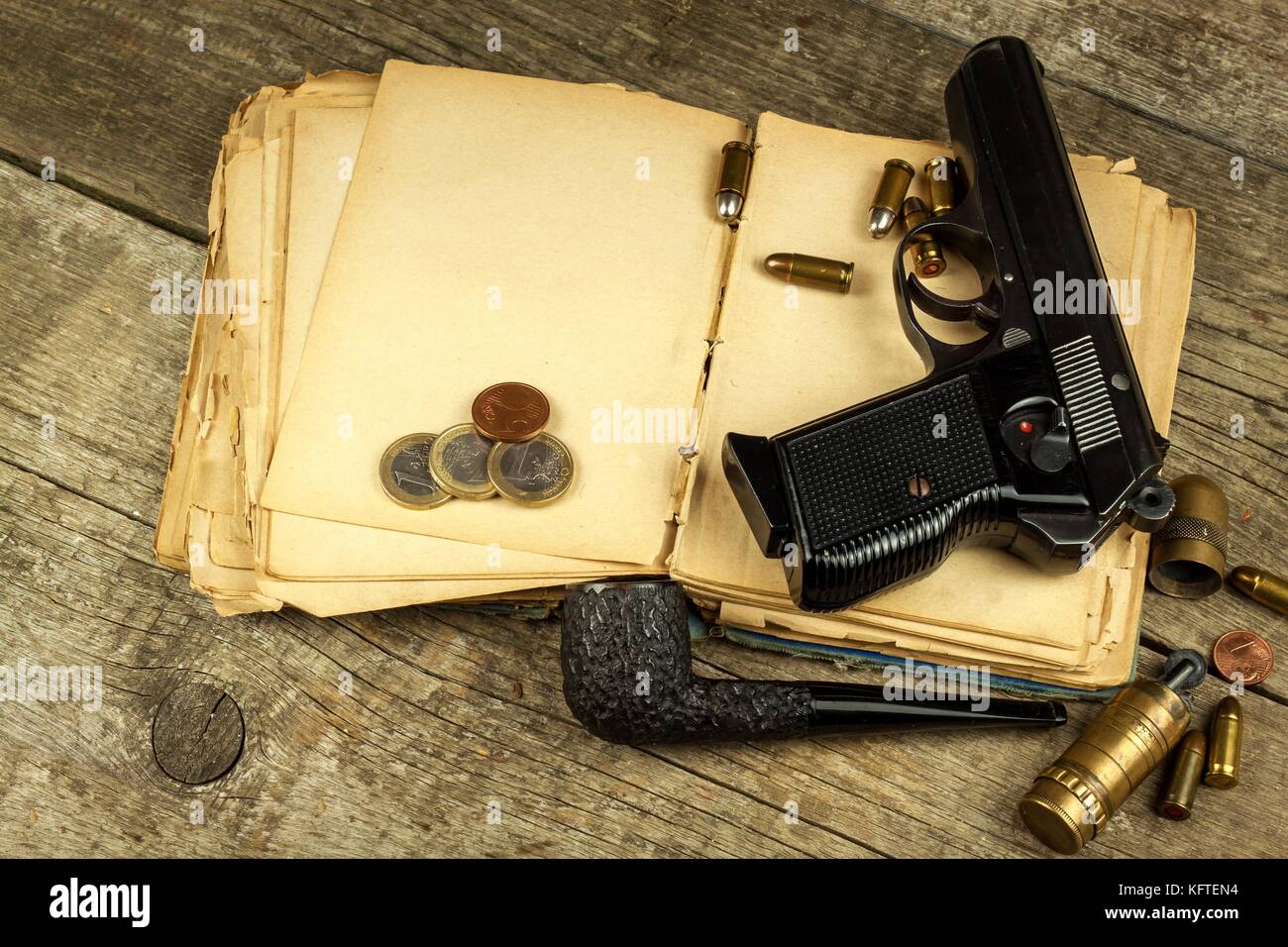 Gun and old book. Detective novel. Wooden tobacco pipe. Pistols and  cartridges on the table Stock Photo