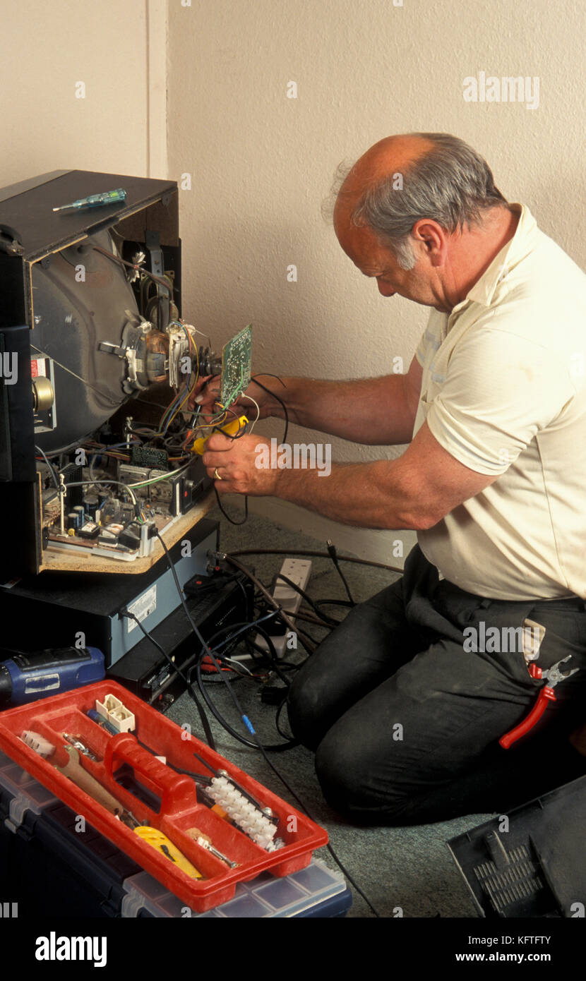 man repairing or taking an old analogue television to pieces Stock Photo