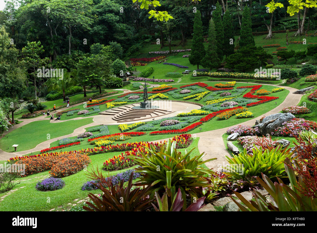 View over the formal garden in the grounds of the Royal Villa at Doi Tung, Northern Thailand. A few people are walking around admiring the plants. Stock Photo