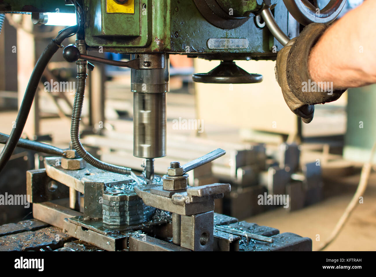 Worker operating stainless steel drilling machine cooled by water Stock Photo