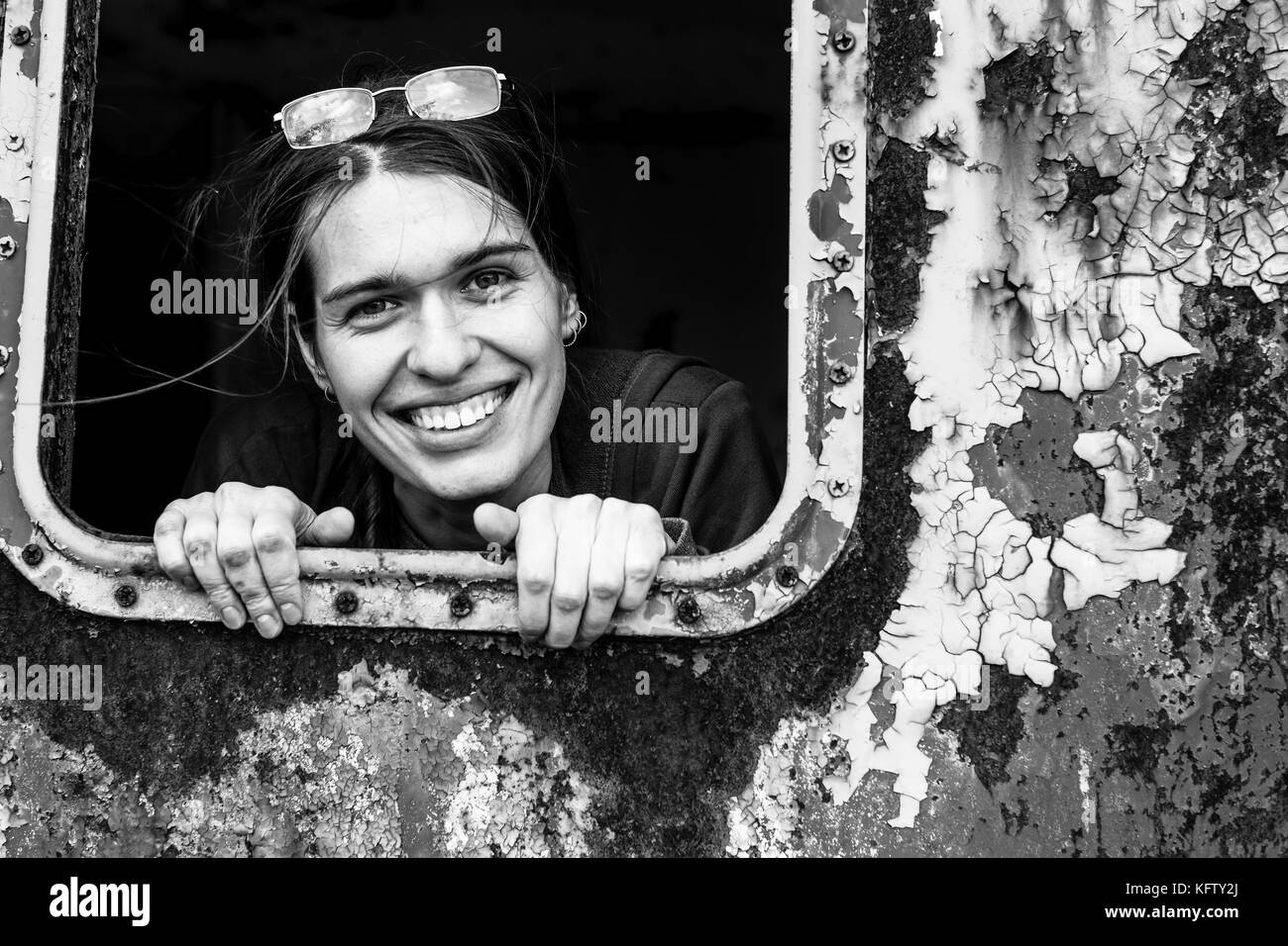 Black and white portrait of a girl in a rusty industrial car. Stock Photo