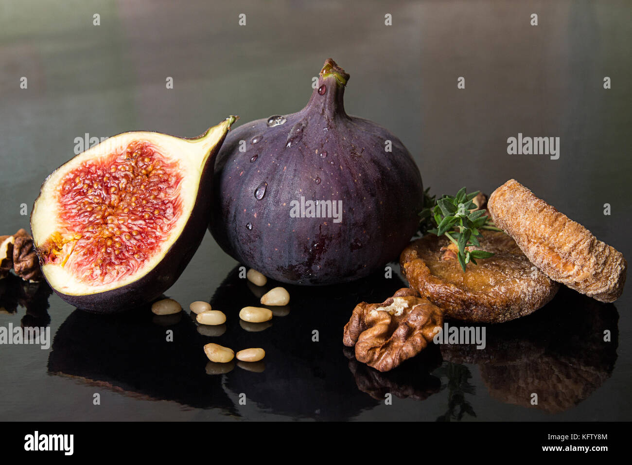 Figs, dried figs, half of fig, walnut and pine nuts on black background. Dieting healthy eating