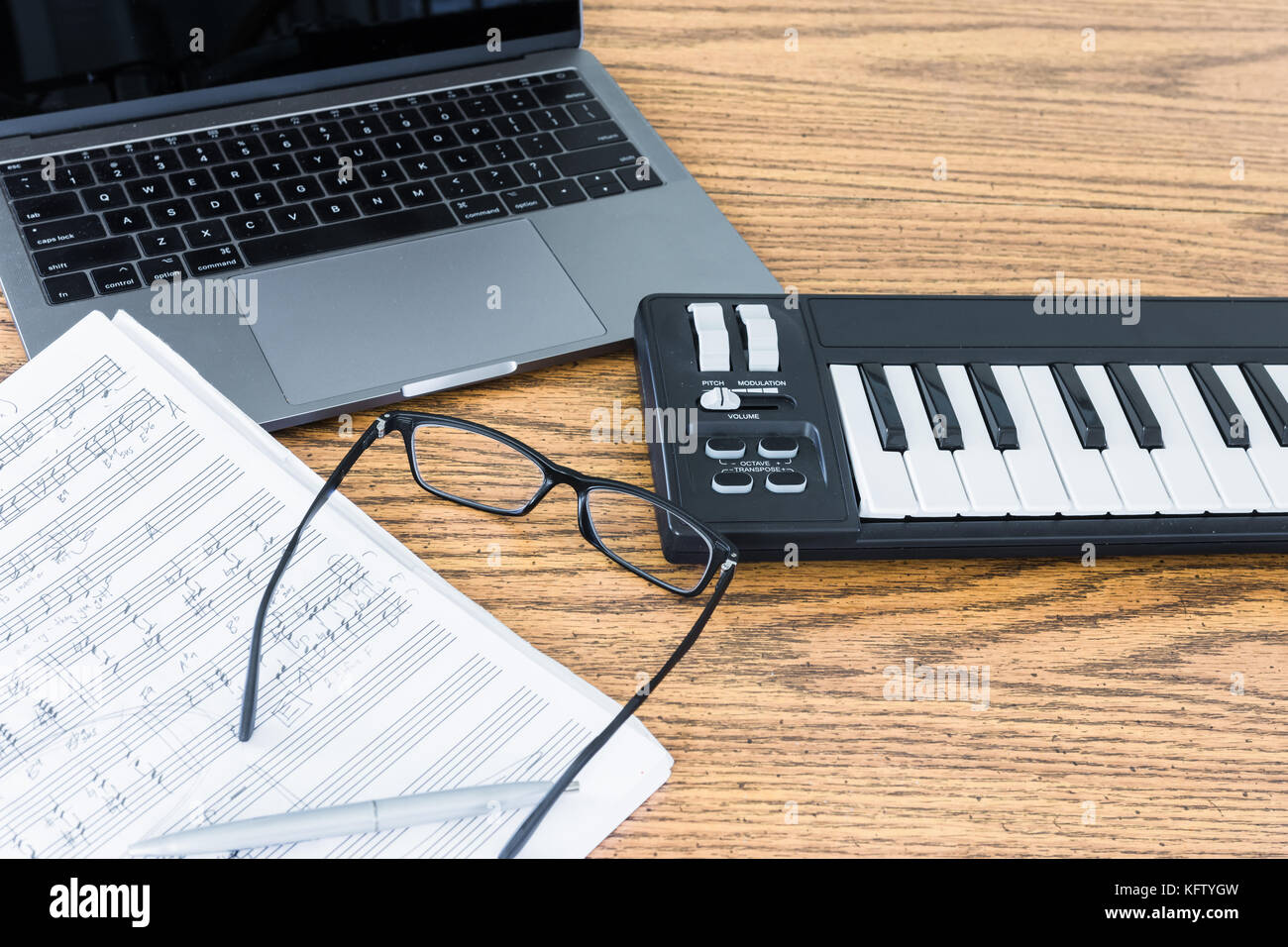 New laptop, midi keyboard or piano, sheet music and black glasses on wooden  table top Stock Photo - Alamy