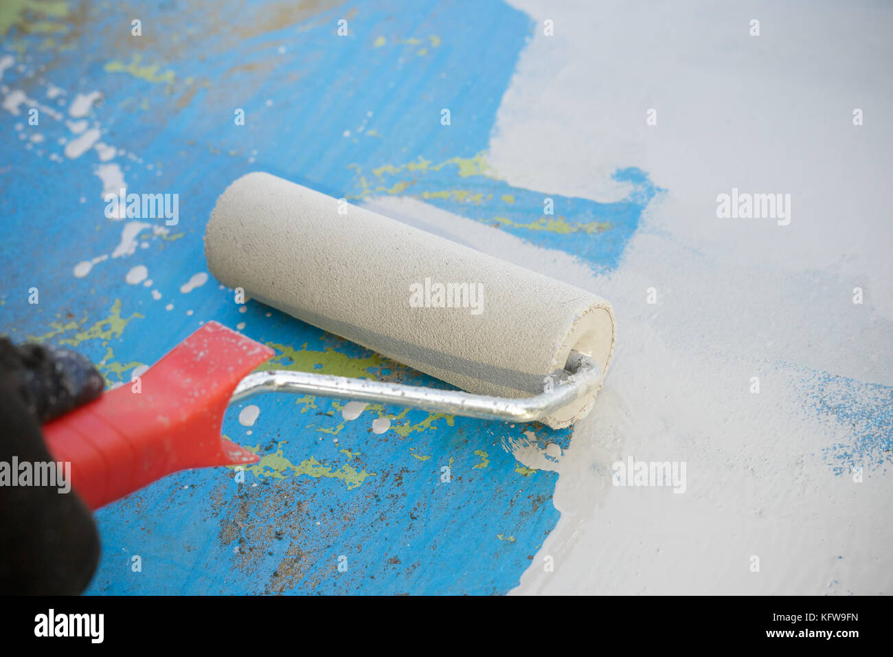 Painting a metal surface with paint primer using a roller. Close up Stock Photo