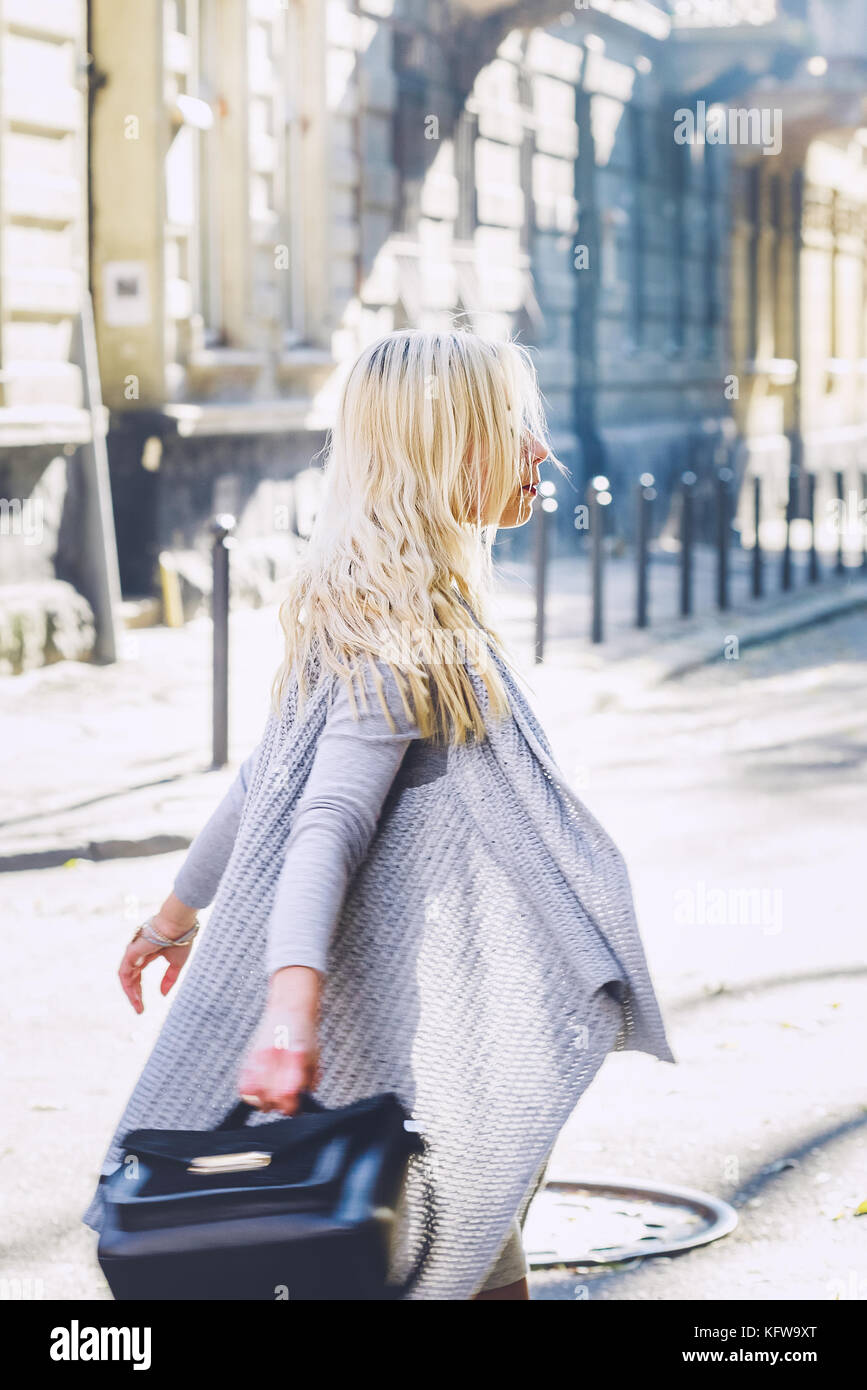 Young stylish blonde business woman wearing grey cardigan and short dress  walking on the old city street. Casual fashion, elegant look Stock Photo -  Alamy