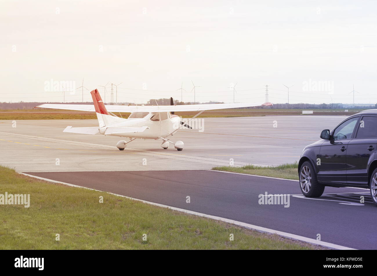 White Small Aircraft and SUV Car Parking on the Runway Rear View Stock Photo