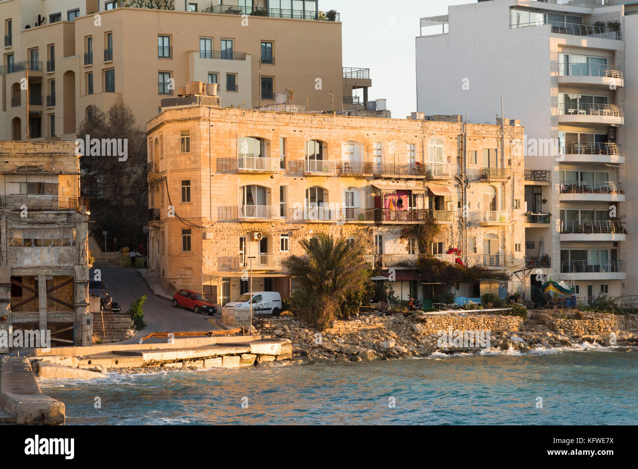 An old stone apartment building at St Julians Bay Malta in early morning sunshine Stock Photo