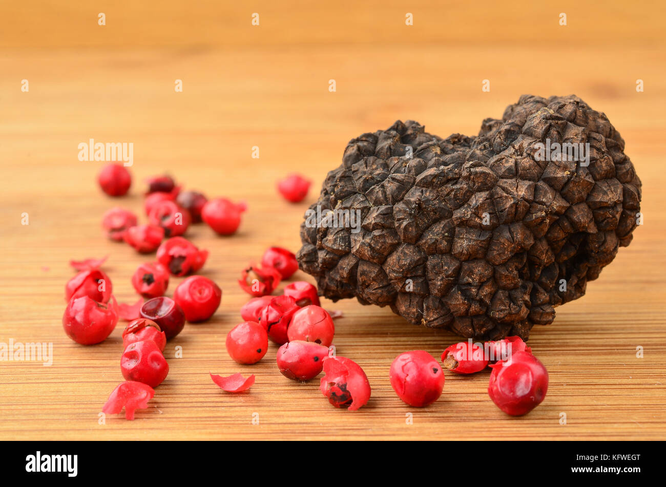One piece of Black truffle, heart shaped, and grains of red pepper on bamboo wooden background, close up view Stock Photo