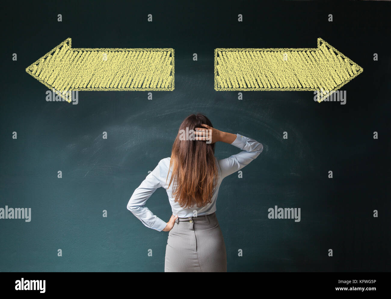 Business woman in front of a blackboard with arrows Stock Photo