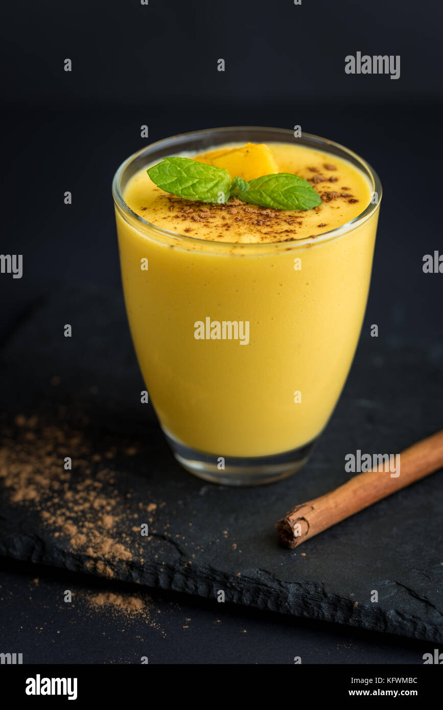 Fresh mango smoothie with cinnamon on a black slate background. Stock Photo