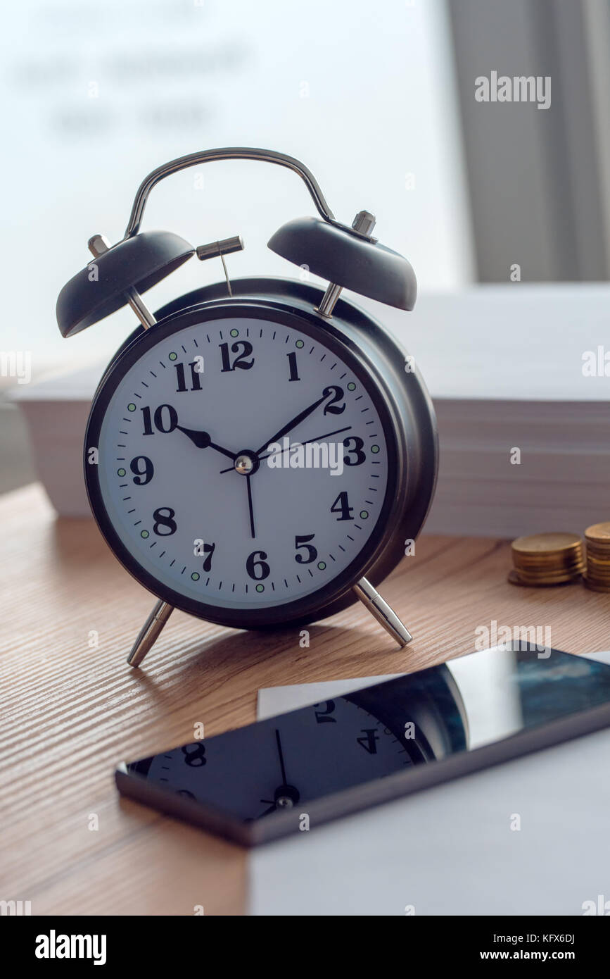 Working hours, vintage clock and mobile phone on business office desk Stock Photo