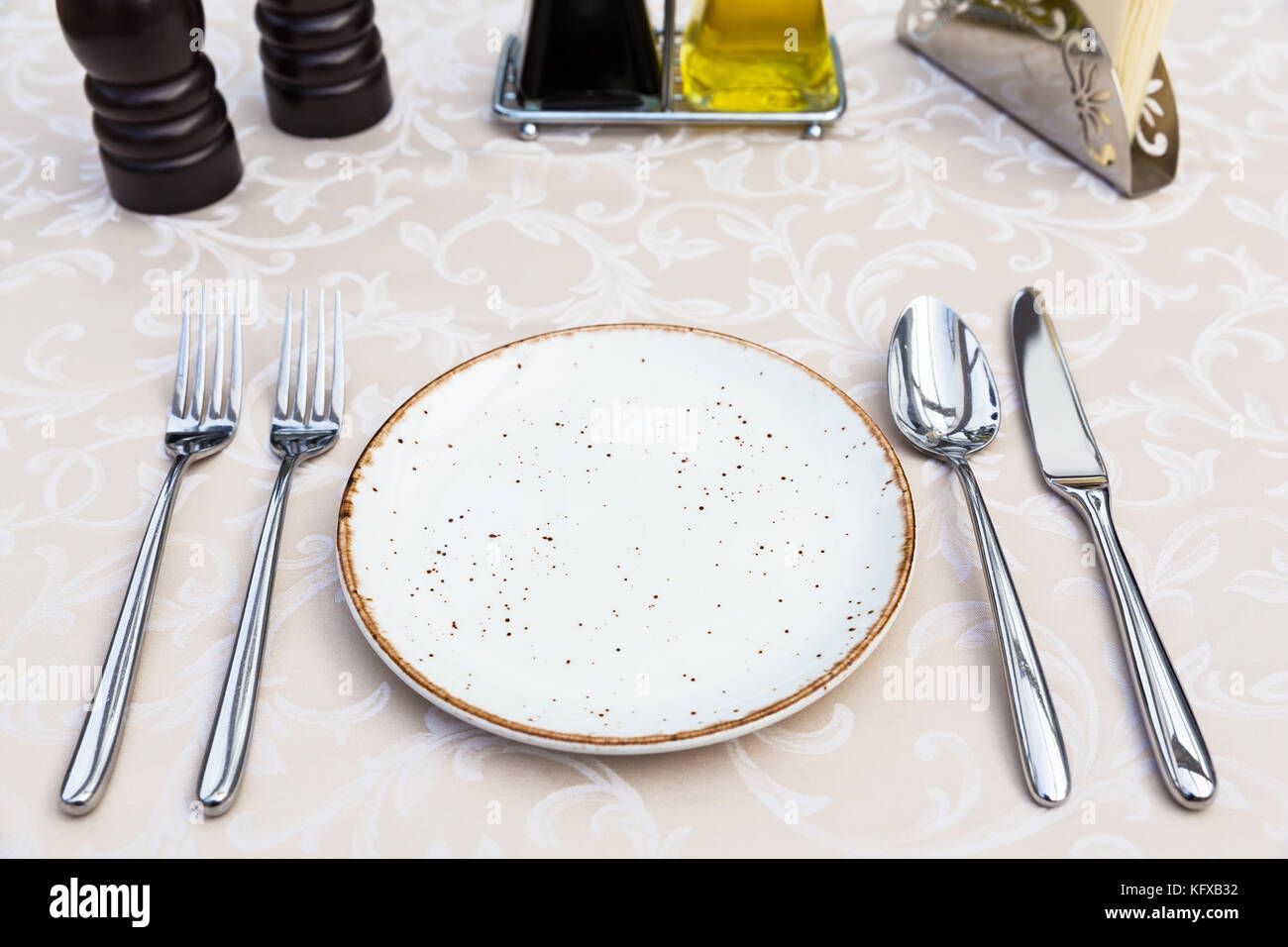 Table setting with plates, knife, fork and spoon, restaurant interior