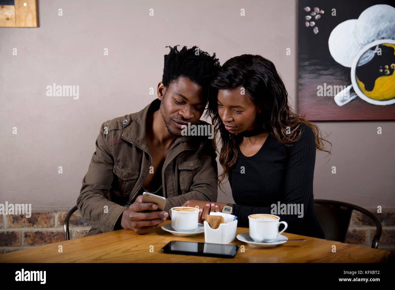 Couple having coffee and looking at a phone Stock Photo